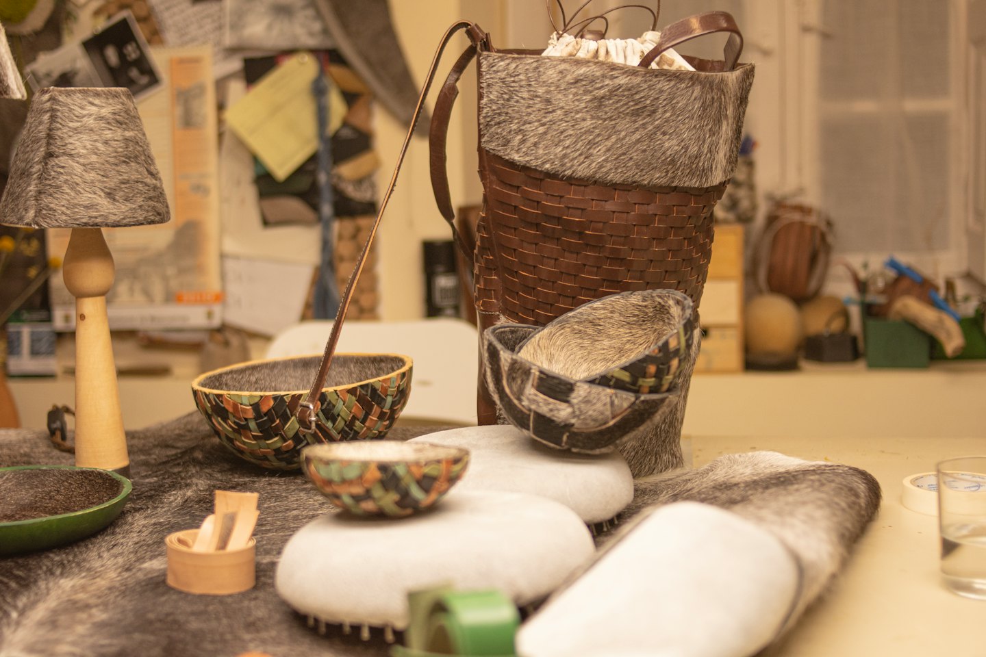 Handcrafted leather and fur items displayed on a table.